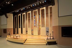 At Concord United Methodist Church in Knoxville, TN, acoustical partitions hide band equipment in a multi-use worship room. Custom cut-outs ensure the space’s stained glass windows are always visible.  